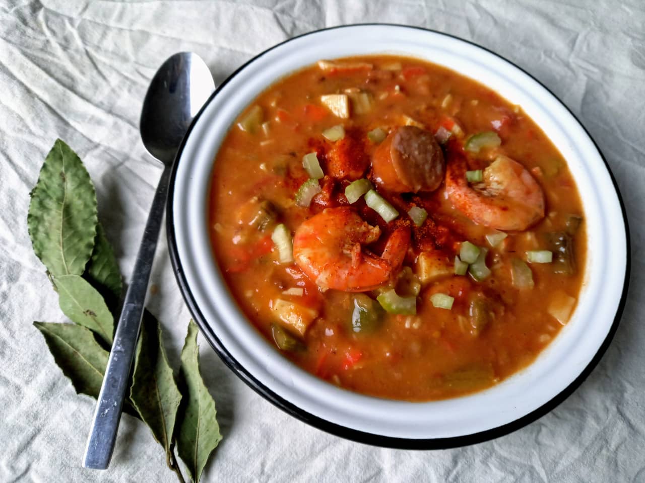 A bowl containing gumbo, with sausage, okra and shrimp.