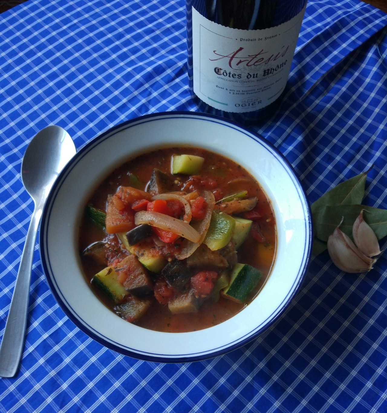 A ratatouille served next to a fine red Burgundy and some spices.